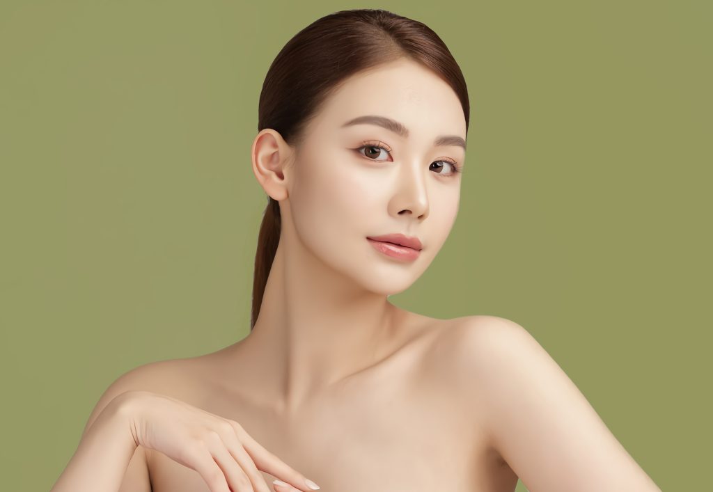 Portrait of a woman with smooth, luminous skin against a soft green background, reflecting healthy complexion and natural beauty inspired by ORY Skincare.