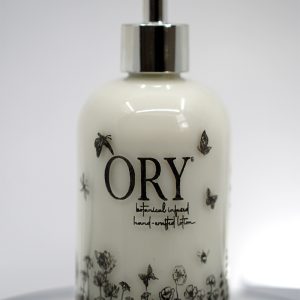 ORY Botanical Garden glass lotion bottle with soft ivory glass, delicate wildflower illustrations, and polished silver pump for personalized skincare.