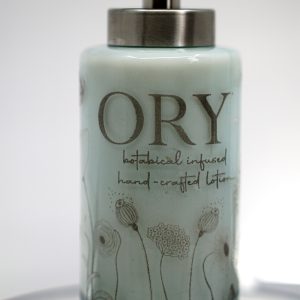 ORY Serenity Blue botanical glass lotion bottle with soft blue tint, delicate floral line illustrations, and brushed silver pump for personalized skincare.