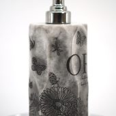 ORY Midnight Garden marble lotion bottle featuring etched butterflies and floral illustrations with polished silver pump, shown at an angled view for personalized skincare.
