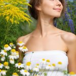 Woman surrounded by chamomile flowers in a garden — natural azulene extract skincare ingredient for ORY Skincare.