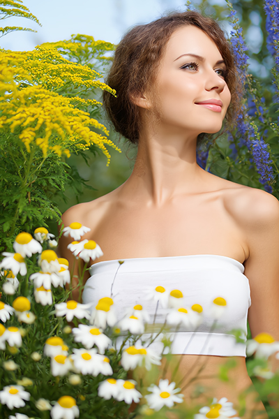Woman surrounded by chamomile flowers in a garden — natural azulene extract skincare ingredient for ORY Skincare.