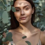 Woman surrounded by eucalyptus leaves representing the purity and clarifying benefits of Eucalyptus (80/82) Essential Oil used in ORY Skincare formulations.