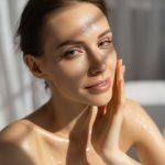 Woman with naturally glowing oily skin touching her cheek, representing ORY Skincare’s customized oily skin treatments for balanced, shine-controlled complexion.