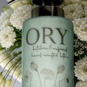 Elegant personalized ORY botanical infused hand and body lotion bottle with pump dispenser, featuring leaf and butterfly designs on floral background, showcasing Oryskincare's custom natural skincare solutions for nourished, hydrated skin.