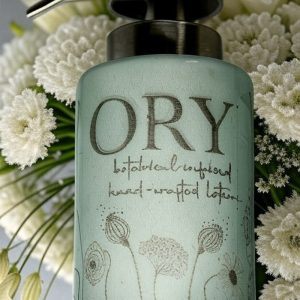 Elegant personalized ORY botanical infused hand and body lotion bottle with pump dispenser, featuring leaf and butterfly designs on floral background, showcasing Oryskincare's custom natural skincare solutions for nourished, hydrated skin.