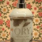 Elegant personalized ORY botanical infused hand and body lotion bottle with pump dispenser, featuring leaf and butterfly designs on floral background, showcasing Oryskincare's custom natural skincare solutions for nourished, hydrated skin.