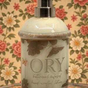 Elegant personalized ORY botanical infused hand and body lotion bottle with pump dispenser, featuring leaf and butterfly designs on floral background, showcasing Oryskincare's custom natural skincare solutions for nourished, hydrated skin.