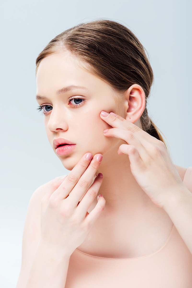 Young woman gently examining her skin while demonstrating a botanical-infused skincare routine designed for sensitive and balanced skin types by ORY Skincare.