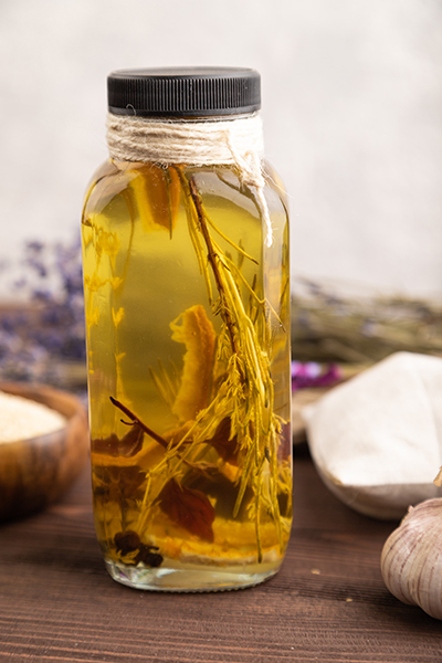 Glass bottle of botanical oil infusion with whole herbs steeped in golden carrier oil, illustrating ORY Skincare’s slow-crafted botanical infusion process.