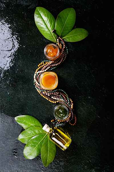 Artisanal botanical infusion with plant oils and extracts arranged in a flowing pattern with fresh green leaves, representing ORY Skincare’s holistic infusion process.