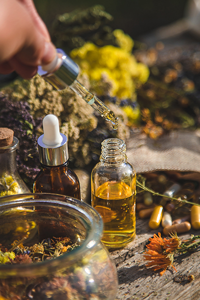 Artisanal botanical infusion process with glass dropper bottles, golden plant-infused oils, and dried herbs used in ORY Skincare formulations.