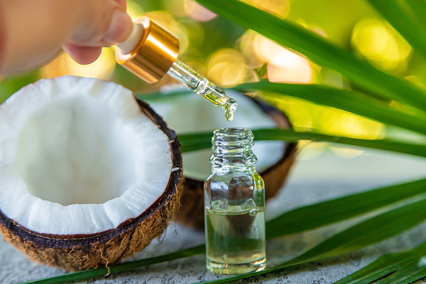 Dropper dispensing coconut and palm oil into a glass bottle beside fresh coconut — natural moisturizing oils for ORY Skincare.