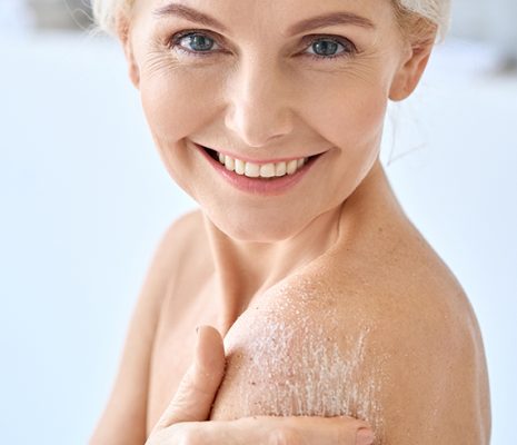Woman applying skincare cream to shoulder, demonstrating emulsifier science that blends oil and water for smooth, hydrated skin in ORY Skincare routines.