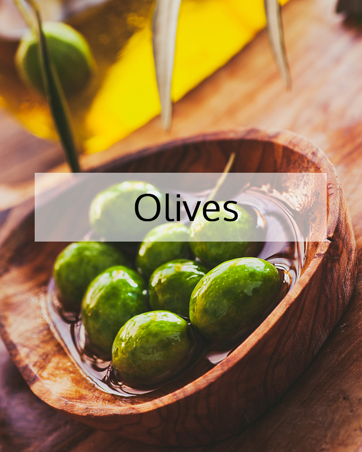 Fresh green olives resting in a wooden bowl with golden olive oil, representing the natural source of olive oil used in ORY Skincare for deep hydration and skin barrier nourishment.