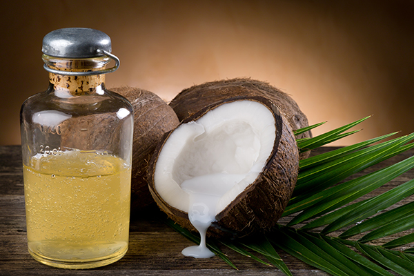 Bottle of coconut and palm oil beside fresh coconuts and palm leaves — natural moisturizing oils for ORY Skincare.