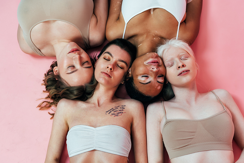 Diverse group of women with different skin tones and textures lying together, representing inclusive skincare for all skin types.
