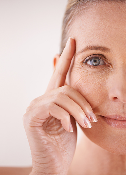 Close-up of mature woman touching eye area, showing fine lines and healthy glowing skin for ORY Skincare mature skincare solutions.