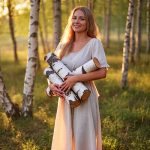 Woman holding birch logs in a sunlit forest — natural birch bark extract skincare ingredient for ORY Skincare.