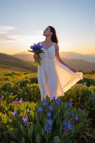 Woman holding blue borage flowers in a mountain meadow at sunset — natural borage seed oil skincare ingredient for ORY Skincare.