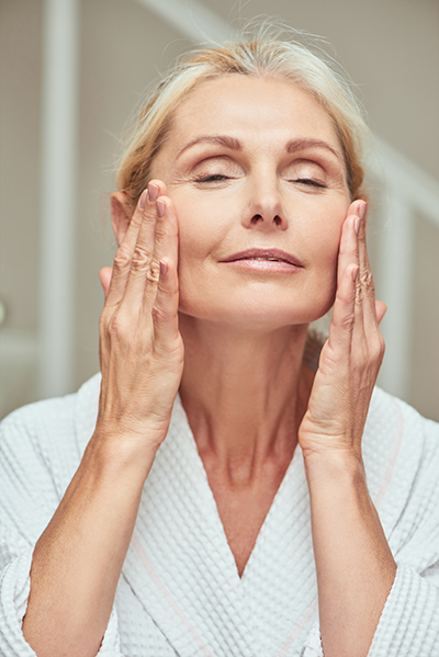 beauty_photoshoot_cleanser_mature_skin Mature woman cleansing and massaging her face, representing ORY Skincare’s hydrating and firming cleanser for mature skin.