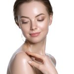 Woman with fresh glowing skin gently touching shoulder, representing ORY Skincare’s cleanser for oily skin that purifies and balances shine.