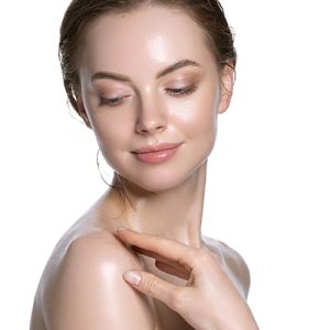 Woman with fresh glowing skin gently touching shoulder, representing ORY Skincare’s cleanser for oily skin that purifies and balances shine.