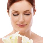 Woman with sensitive skin gently holding white lilies, symbolizing ORY Skincare’s gentle botanical cleanser for sensitive skin.