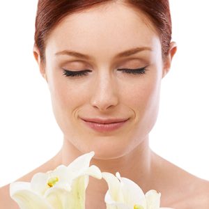 Woman with sensitive skin gently holding white lilies, symbolizing ORY Skincare’s gentle botanical cleanser for sensitive skin.