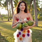 Woman holding coconuts in a tropical grove — coconut fragrance oil used in ORY Skincare for warm, tropical aroma.