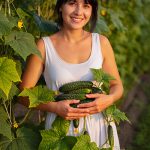 Woman holding fresh cucumbers in a garden — cucumber extract hydrating and soothing skincare ingredient for ORY Skincare.