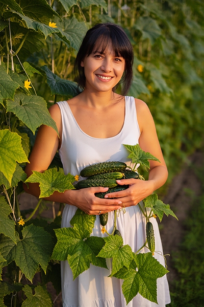 Woman holding fresh cucumbers in a garden — cucumber extract hydrating and soothing skincare ingredient for ORY Skincare.
