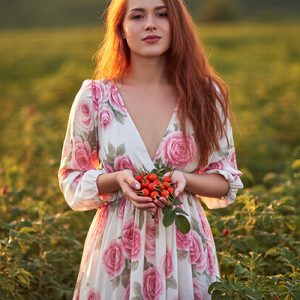 Woman holding fresh rosehips in a field, representing rosehip extract as a natural ORY Skincare ingredient rich in antioxidants and skin-nourishing nutrients.