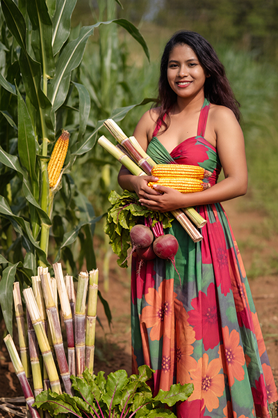 Woman holding sugarcane and corn in a field, representing sodium lactate as a naturally derived ORY Skincare ingredient that supports hydration and moisture balance.