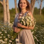 Woman holding a bouquet of chamomile flowers in a sunlit field — natural bisabolol skincare ingredient for ORY Skincare.