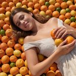 Woman lying on a bed of citrus fruits — natural citrate (citric acid) skincare ingredient for ORY Skincare.
