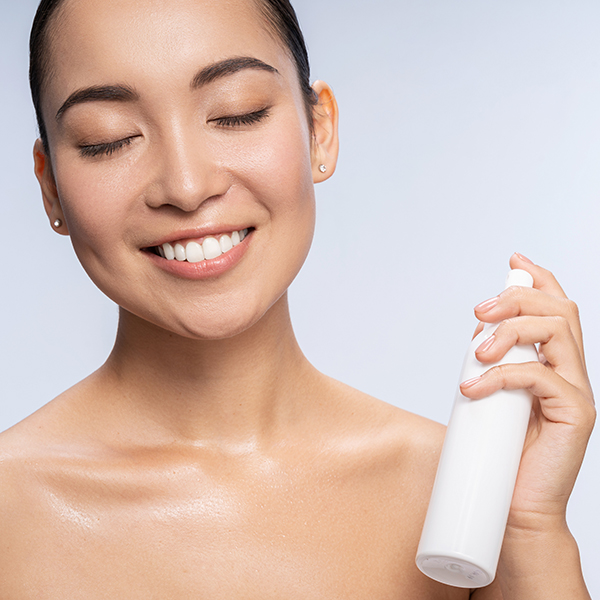 Woman applying bi-phasic infusion skincare mist, illustrating a dual-phase oil and water formula that refreshes, hydrates, and nourishes skin.