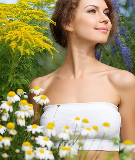 Woman surrounded by chamomile flowers in a garden — natural azulene extract skincare ingredient for ORY Skincare.