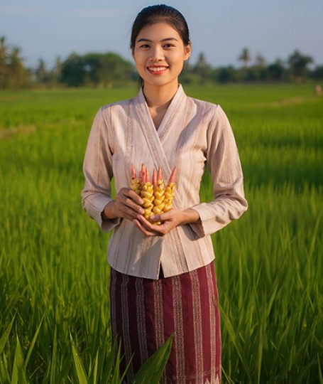 Woman standing in a green field holding fresh turmeric roots, representing ORY Skincare’s use of turmeric extract as a natural antioxidant ingredient known for brightening, calming, and skin-balancing benefits.